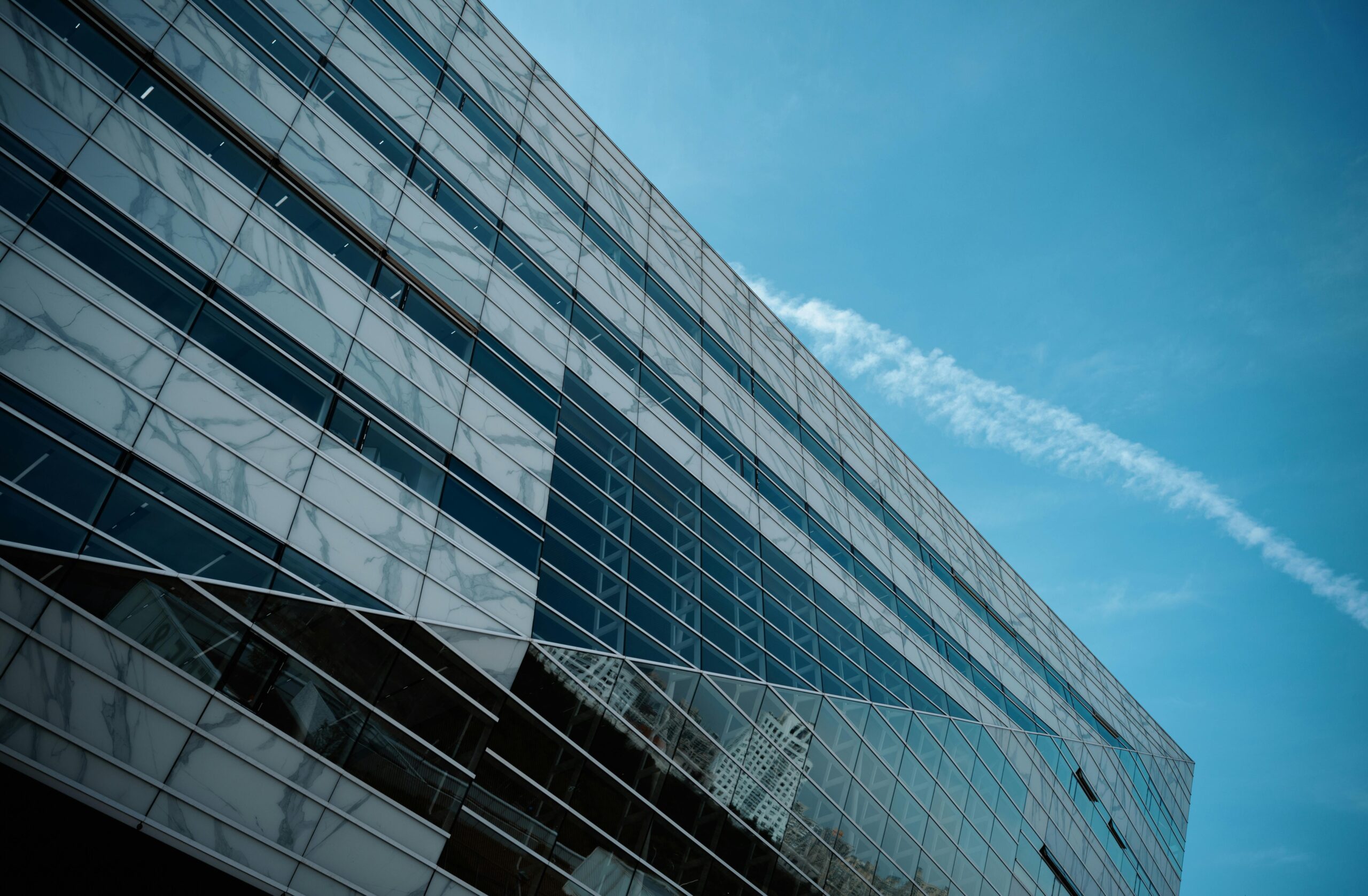 A striking low angle view of a modern glass building against a clear blue sky, emphasizing urban architecture.